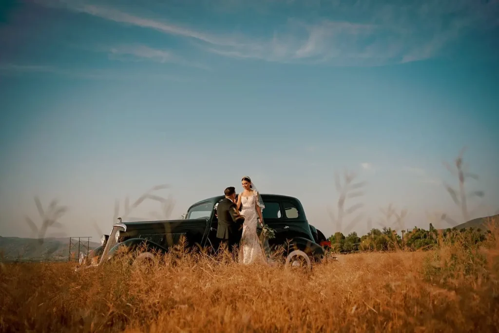 Couple beside a vintage car in the golden fields of Valle de Guadalupe