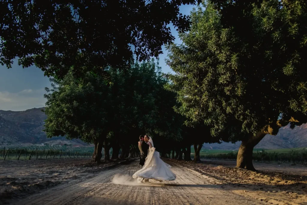 Bride and groom dancing on a tree-lined dirt road in Valle de Guadalupe